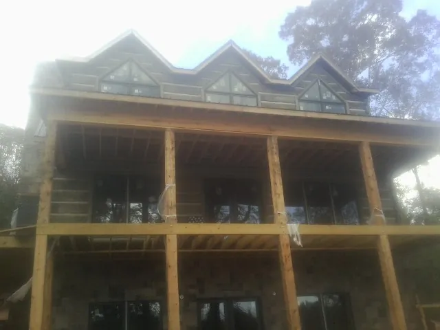 Dormers and porch framing on a large log home under construction — Roof Coating work by our crew in Roanoke